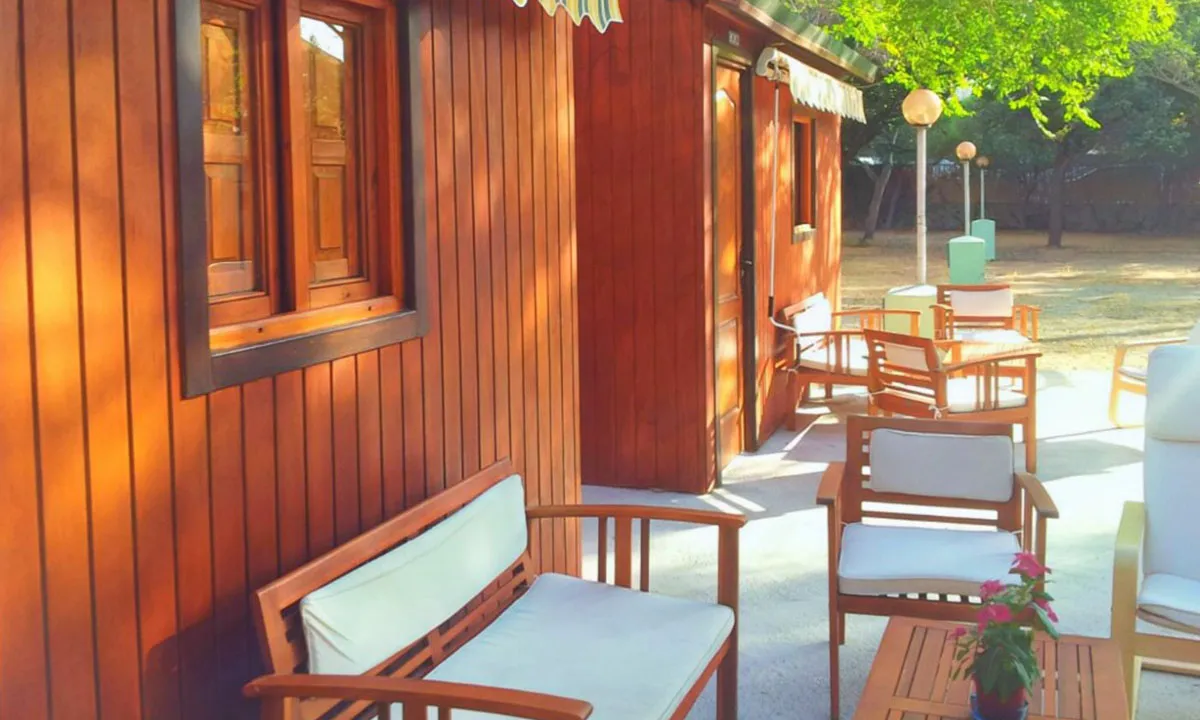 Terraza de la casita de madera con mesa y sillas a la sombra