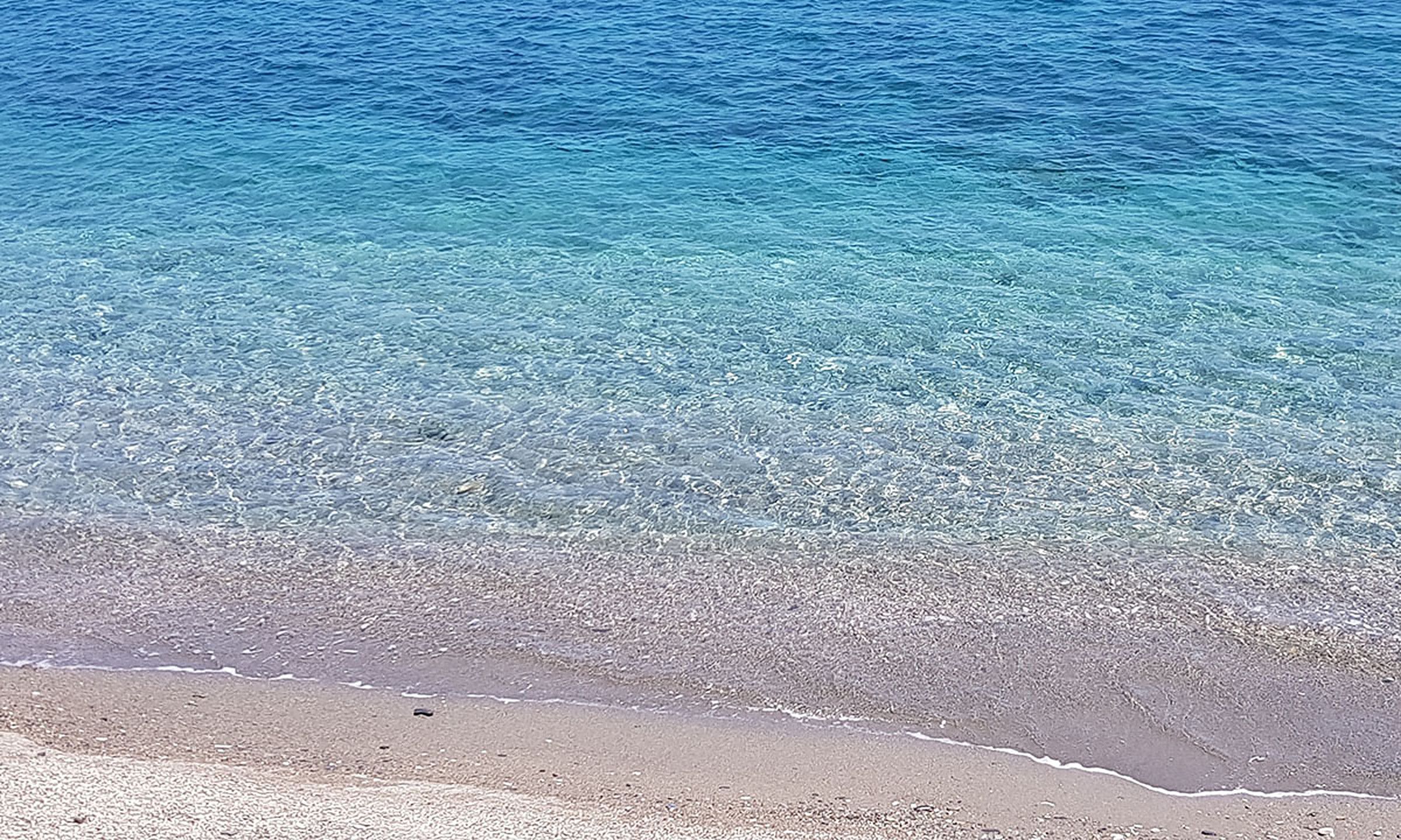 Orilla de la playa de Castell de Ferro, con aguas turquesas y cristalinas sobre arena y piedrecitas
